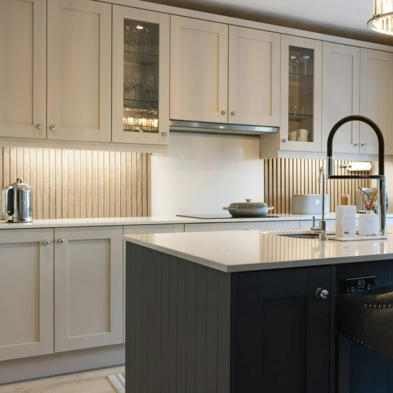 Peak Cabinets modern kitchen with cream glass-front uppers, dark lower cabinetry, metal backsplash, and black faucet.