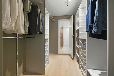 Peak Cabinets reach-in closet with hanging rods, wire shelving, and organized clothing storage.