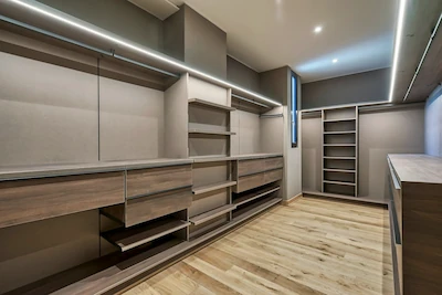 Peak Cabinets luxury walk-in closet with cream cabinetry, dark wood accents, shelving, and recessed ceiling lighting.